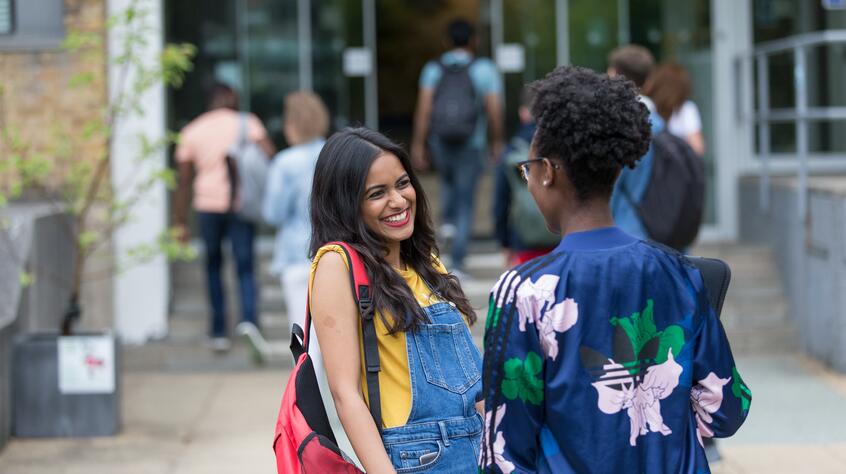 Two students outside, laughing and talking. 