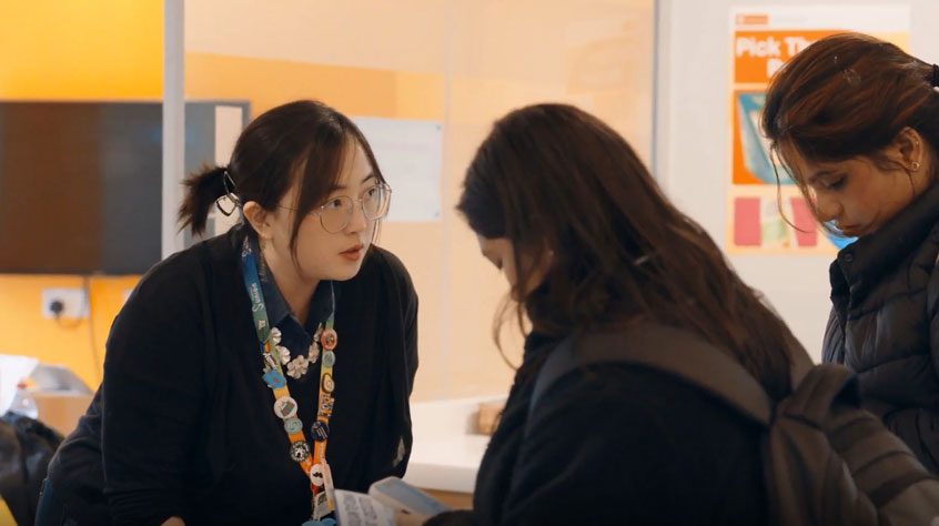 Three women engaged in conversation at a table, sharing ideas and laughter in a friendly setting.