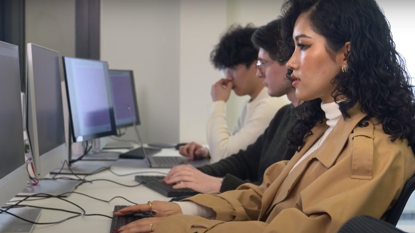 Computer science students sat at their desks working on computers