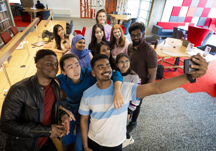 A group of students on University of Leicester campus smiling while taking a selfie