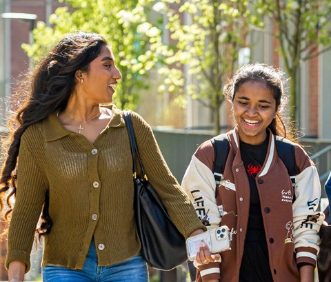 Three women walking, talking and smiling.